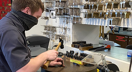 A key being stamped with identifying letters and numbers.